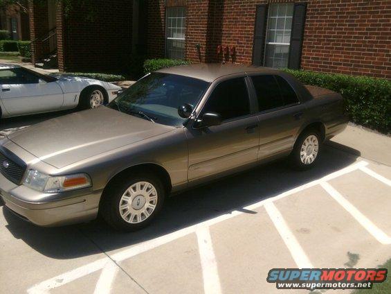 Gold 2003 Ford Crown Victoria parked next to a white sports car