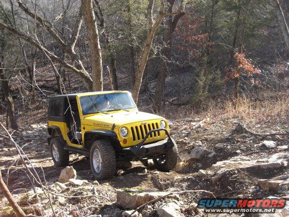 Yellow Jeep Wrangler Rubicon on a rocky trail, front-left quarter view
