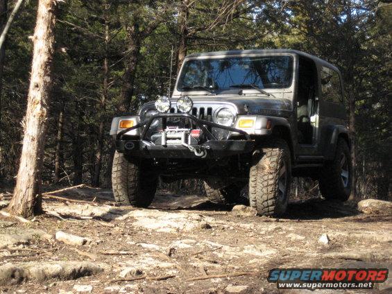 Gray 2005 Jeep Wrangler with winch and off-road tires on a rocky trail