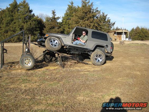 Gray 2005 Jeep Wrangler on a metal ramp with a person inside