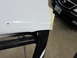 1987 Dodge 1500 - Close-up of a white car door edge being worked on, with a dark vehicle visible in the background.