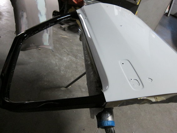 Car door painted white with black window trim, mounted on a stand
