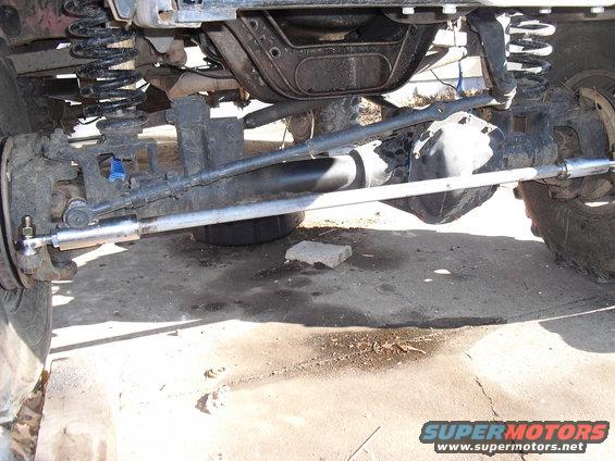 Close-up of vehicle's front axle, steering linkage, and suspension components