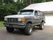 1988 Ford Bronco - This gray Ford Bronco is shown from a three-quarter front angle, parked on an asphalt surface near a building.
