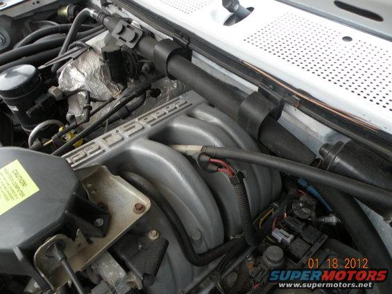 Engine bay with silver intake manifold reading 'COBRA'. Yellow caution sticker visible