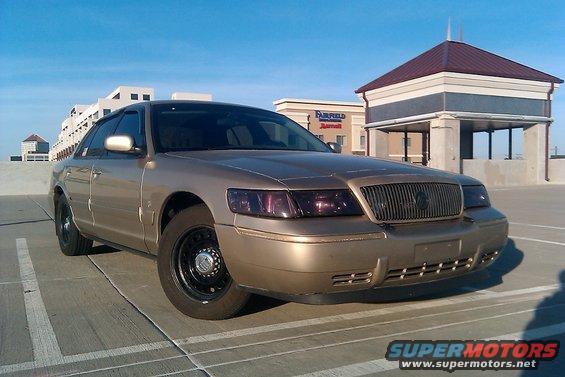 Gold 2000 Mercury Grand Marquis with black steel wheels parked on a rooftop