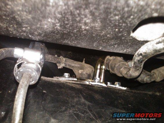 Fuel lines attached to a black surface with metal clamps and bolts