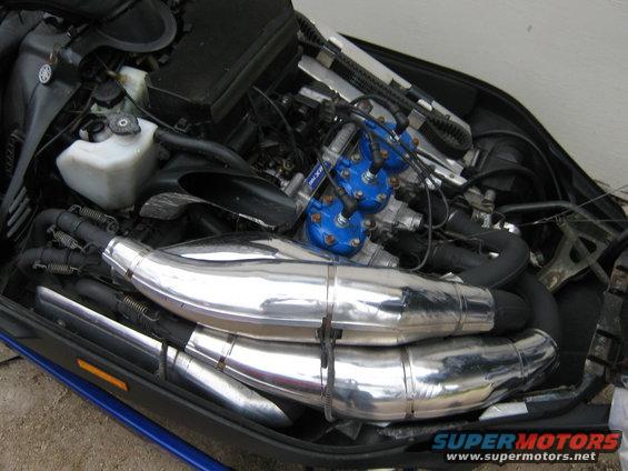 snowmobile engine with dual chrome exhaust pipes and blue ignition coils