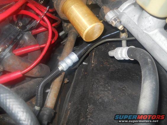 Engine bay with red spark plug wires, brass fitting, and hoses