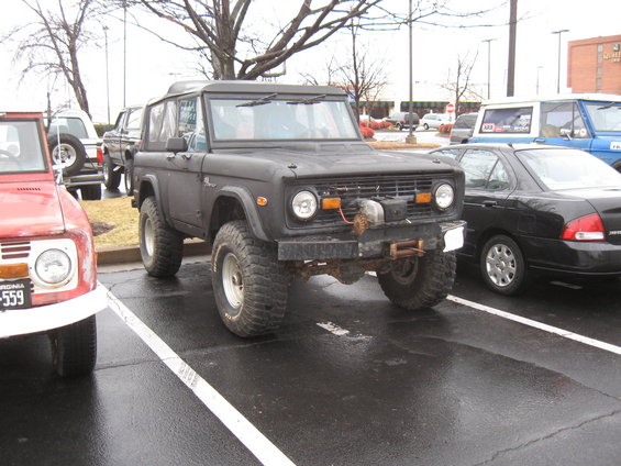 Black Ford Bronco with winch and aftermarket bumper, parked in a lot