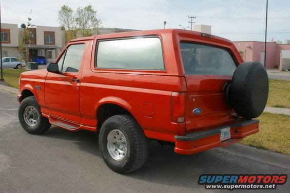 Red 1995 Ford Bronco parked on street, rear quarter view. Spare tire mounted on back
