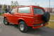 1995 Ford Bronco - This red Ford Bronco is shown from the rear passenger side, a spare tire on the tailgate.