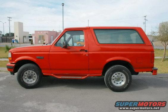 Red Ford Bronco SUV, side view, showing its two-door body and aftermarket wheels