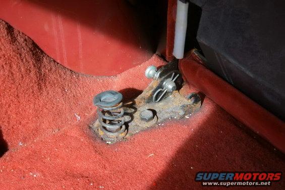 Red carpet with rusted seat mounting bracket and spring mechanism