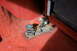 1995 Ford Bronco - Close-up view of a rusted seat mounting bracket with a spring mechanism on red carpet inside a vehicle.