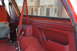 1995 Ford Bronco - Interior view of a red SUV, showing the seatbelt and tools on the floor, with houses visible through the window.