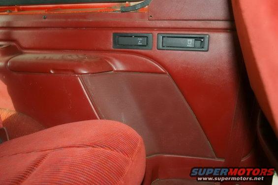 Red fabric seat and red plastic door panel with two black buttons and a small compartment