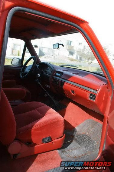 Red interior of a 1995 Ford Bronco, showing the dashboard, seats, and door panel