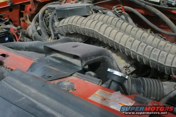 Red engine bay with dusty air intake hoses and a radiator cap
