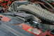 1995 Ford Bronco - Close-up of a dusty engine bay with prominent air intake hoses and a red radiator cover.