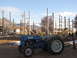 1995 Ford Bronco - A blue Ford tractor sits in a dirt lot with mountains in the background and a partially constructed wooden frame.