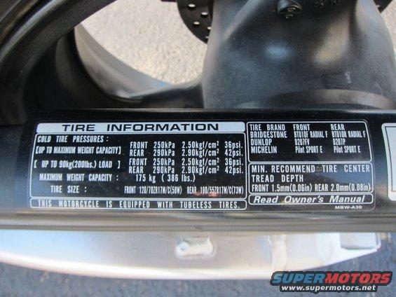 Motorcycle tire information sticker showing cold tire pressures, maximum weight capacity, tire size, tire brands, and minimum recommended tread depth