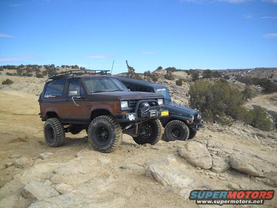 Brown Ford Bronco II with roof rack and off-road tires parked on rocky terrain