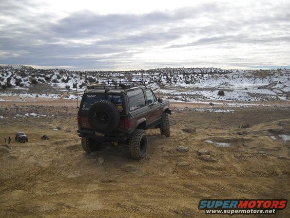 Brown SUV with spare tire on rear, off-road tires, and roof rack