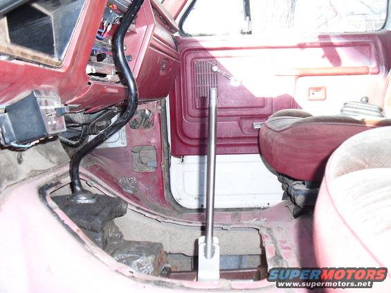 Vehicle interior with red upholstery and floor, showing a floor shifter and exposed metal