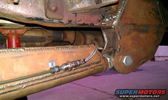 Close-up of custom suspension modification with brake line attached to a metal tube
