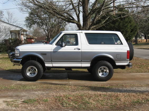 Side view of a white and silver 1994 Ford Bronco with a spare tire on the back