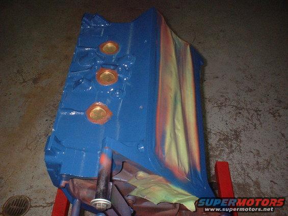 Blue painted engine block with orange and yellow spray paint streaks, on a red stand