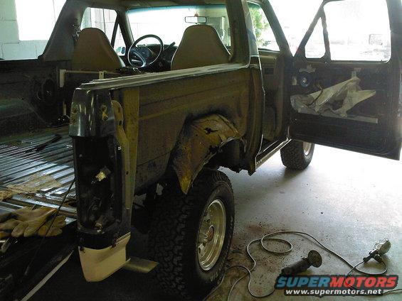 Ford Bronco in disrepair, viewed from the rear passenger side with doors open and interior exposed