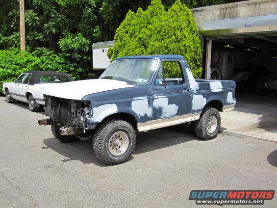 1992 Ford Bronco with primer patches on body, hood is white, front grille missing