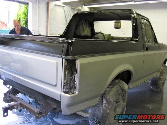 1992 Ford Bronco with rear quarter panel removed, undergoing repairs in a garage