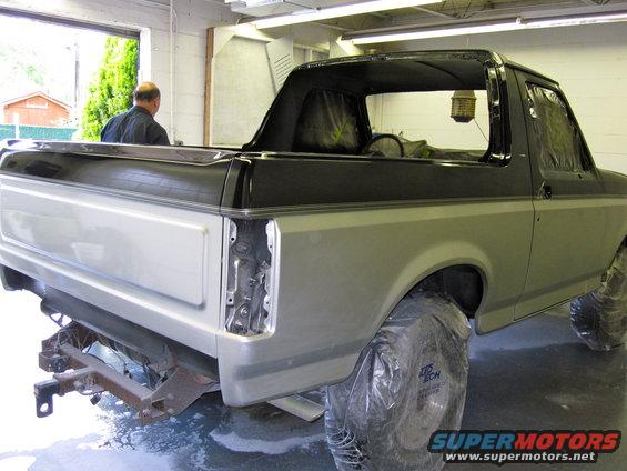 Two-tone silver and black Ford Bronco with rear bumper removed, undergoing repairs