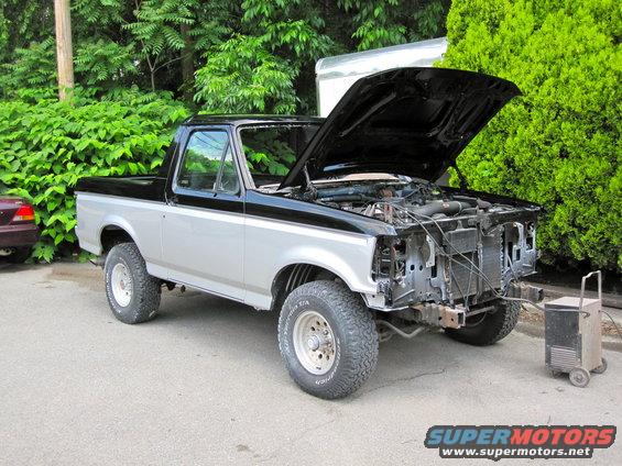 Two-tone black and silver 1992 Ford Bronco with hood open and front grille removed