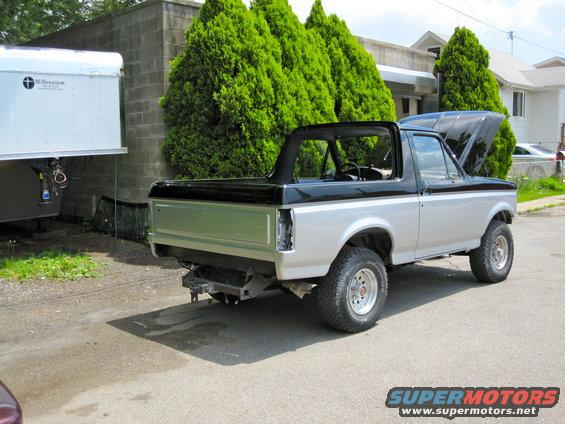 Ford Bronco with removable top, hood open, parked next to a trailer
