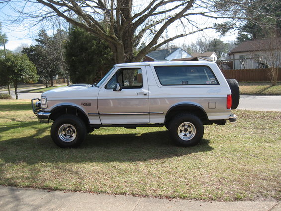 Side view of a white and tan 1994 Ford Bronco with a spare tire on the back