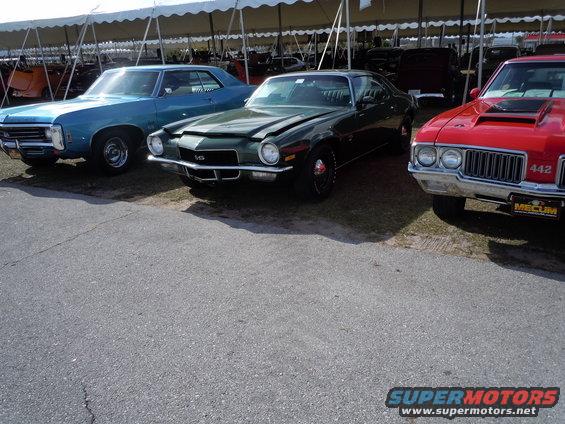 Green muscle car, 3q-front view. Hood is open