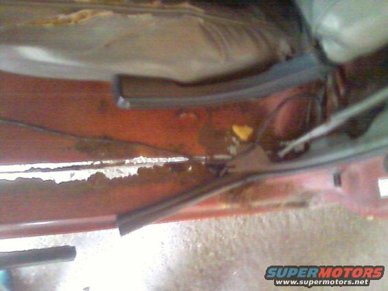 rusted red metal panel with black rubber trim and some yellow debris