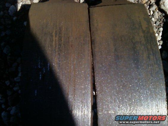 Two worn brake pads with rust and water marks