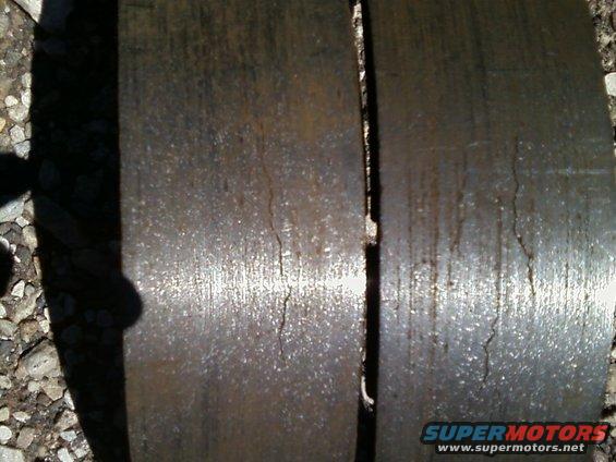 Two heavily rusted and cracked brake rotors, one with a shadow cast on it