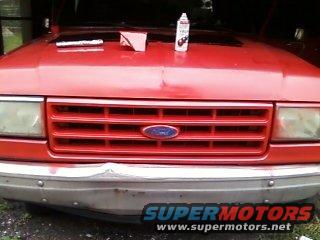 Front of a red pickup truck with hood open. A can of spray paint and a box are on the hood