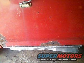 Close-up of rusted lower door panel with metal patch repair