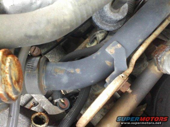 Close-up of engine hoses and metal clamps, some showing rust