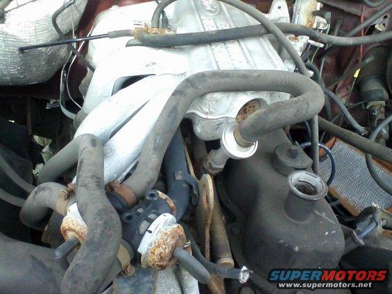 Engine bay with hoses and metal components. Watermark reads "SUPERMOTORS www.supermotors.net"