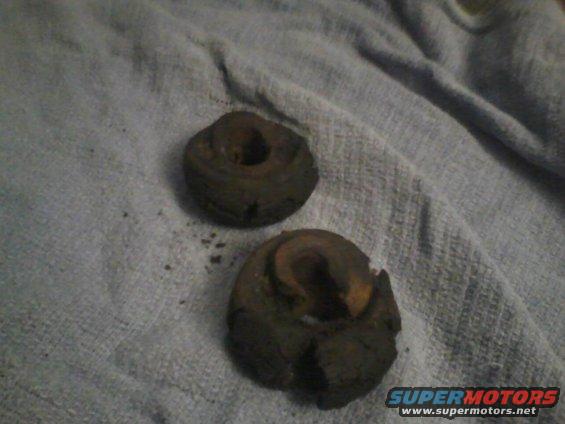 Two rusty, circular metal parts with holes in the center lie on a grey cloth. A Supermotors logo is visible in the lower right corner
