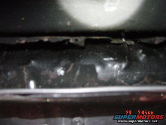 Close-up of rusted vehicle frame underside with some debris
