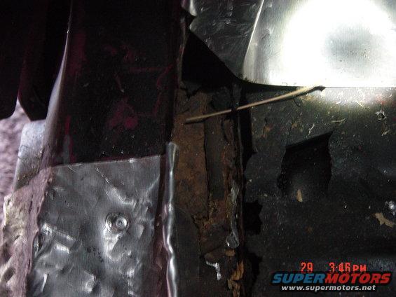 Close-up of rusted metal and a patch job on what looks like a vehicle's undercarriage or wheel well